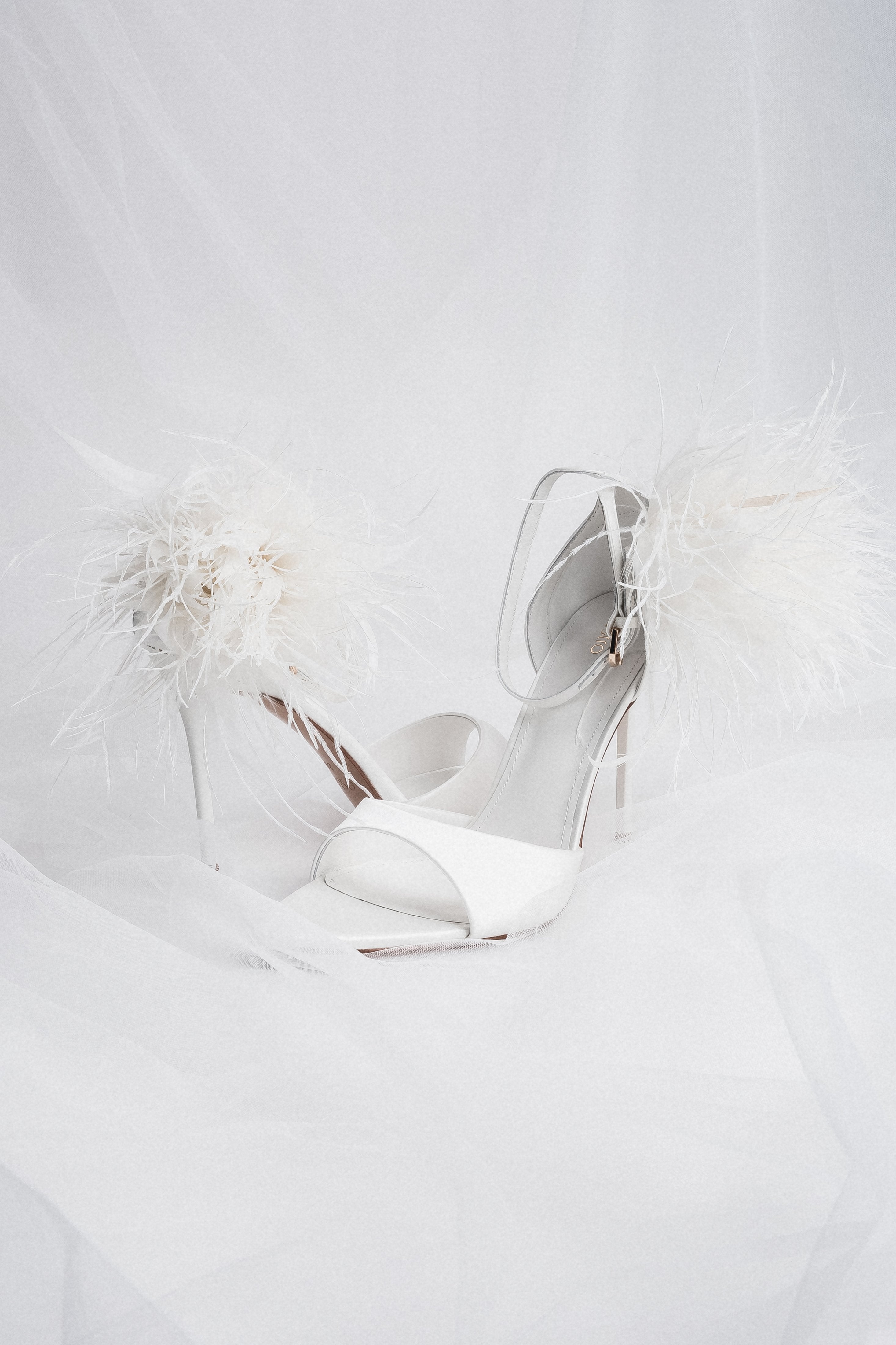 Milchweiße Damen-Sandalette mit Federapplikation in künstlerischer Detailansicht