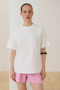 Model trägt milchweißes Damen-T-Shirt im Boxy-Schnitt Vorderansicht