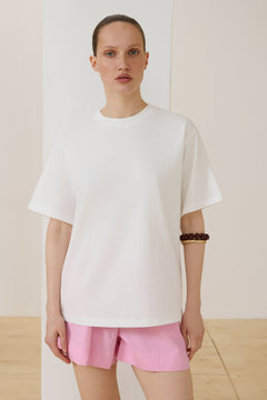 Model trägt milchweißes Damen-T-Shirt im Boxy-Schnitt Vorderansicht