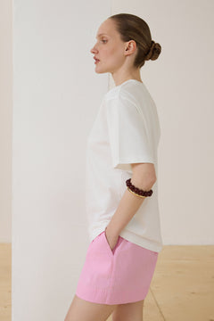 Seitenprofil des Models mit weißem Oversize-T-Shirt und pinken Shorts