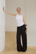 Model in milchweißem ärmellosem Top und schwarzer weiter Hose