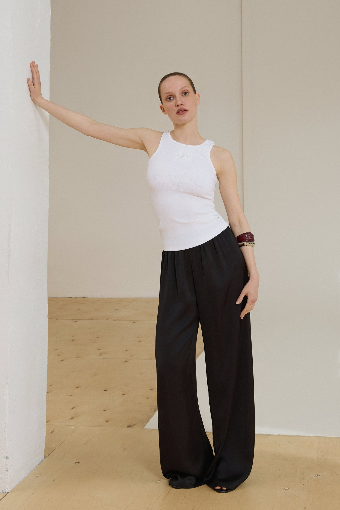 Model in milchweißem ärmellosem Top und schwarzer weiter Hose
