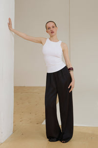 Model in milchweißem ärmellosem Top und schwarzer weiter Hose