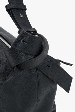 Detailansicht des skulpturalen Zierknotens am Riemen der schwarzen Ledertasche