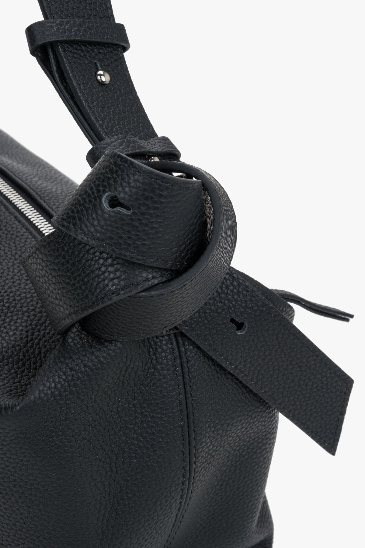 Detailansicht des skulpturalen Zierknotens am Riemen der schwarzen Ledertasche