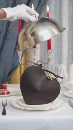 Kreative Lifestyle-Inszenierung (Video/Bild) der Ledertasche unter einer silbernen Servierglocke