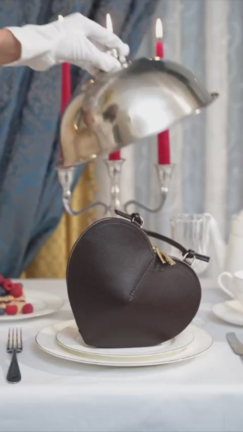 Kreative Lifestyle-Inszenierung (Video/Bild) der Ledertasche unter einer silbernen Servierglocke