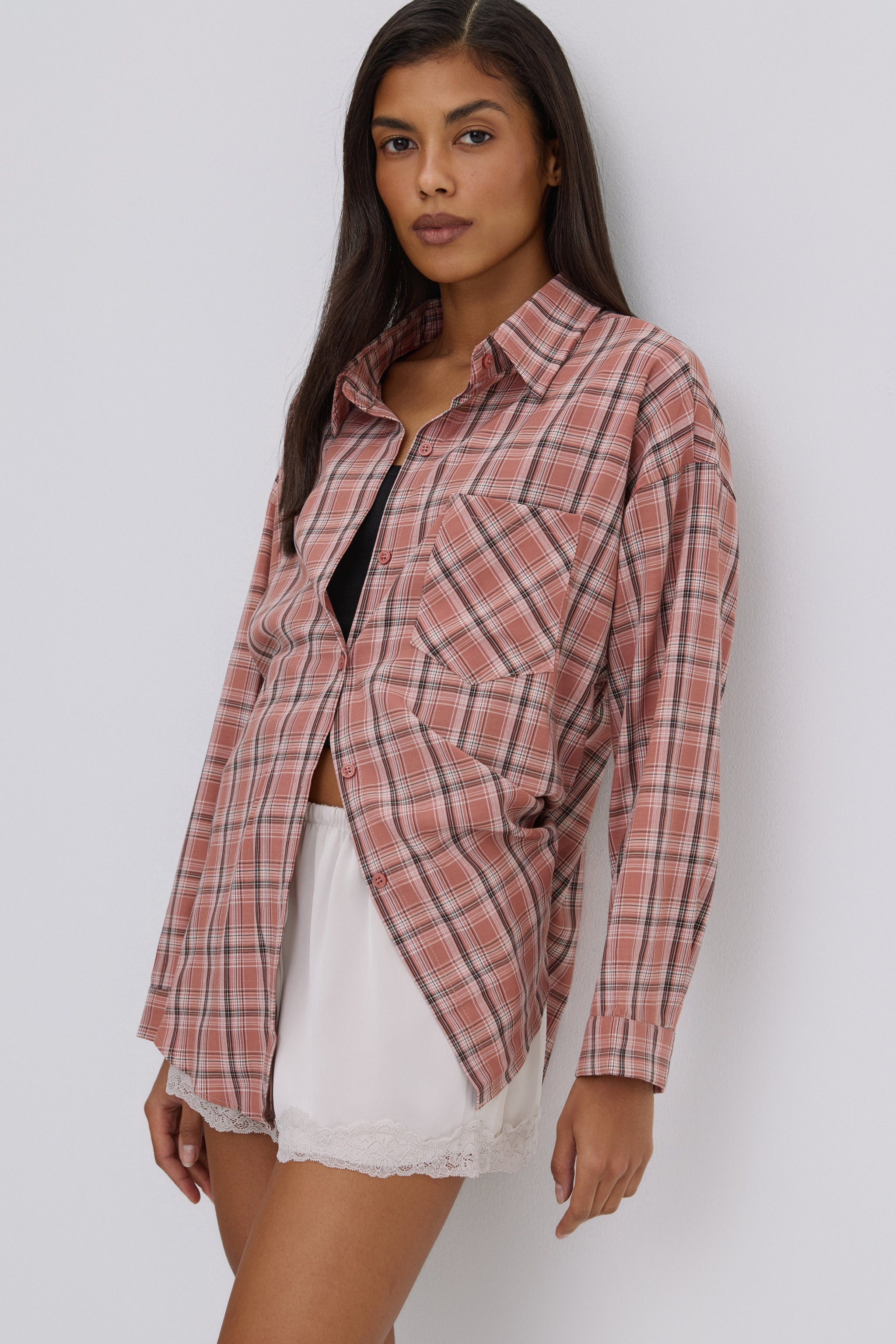 Seitenansicht des Models, das die lässige rosa Karo-Hemdbluse mit einer braunen Tasche kombiniert