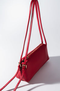 Schrägansicht der roten länglichen Leder Schultertasche mit goldener Schließe und langen Riemen