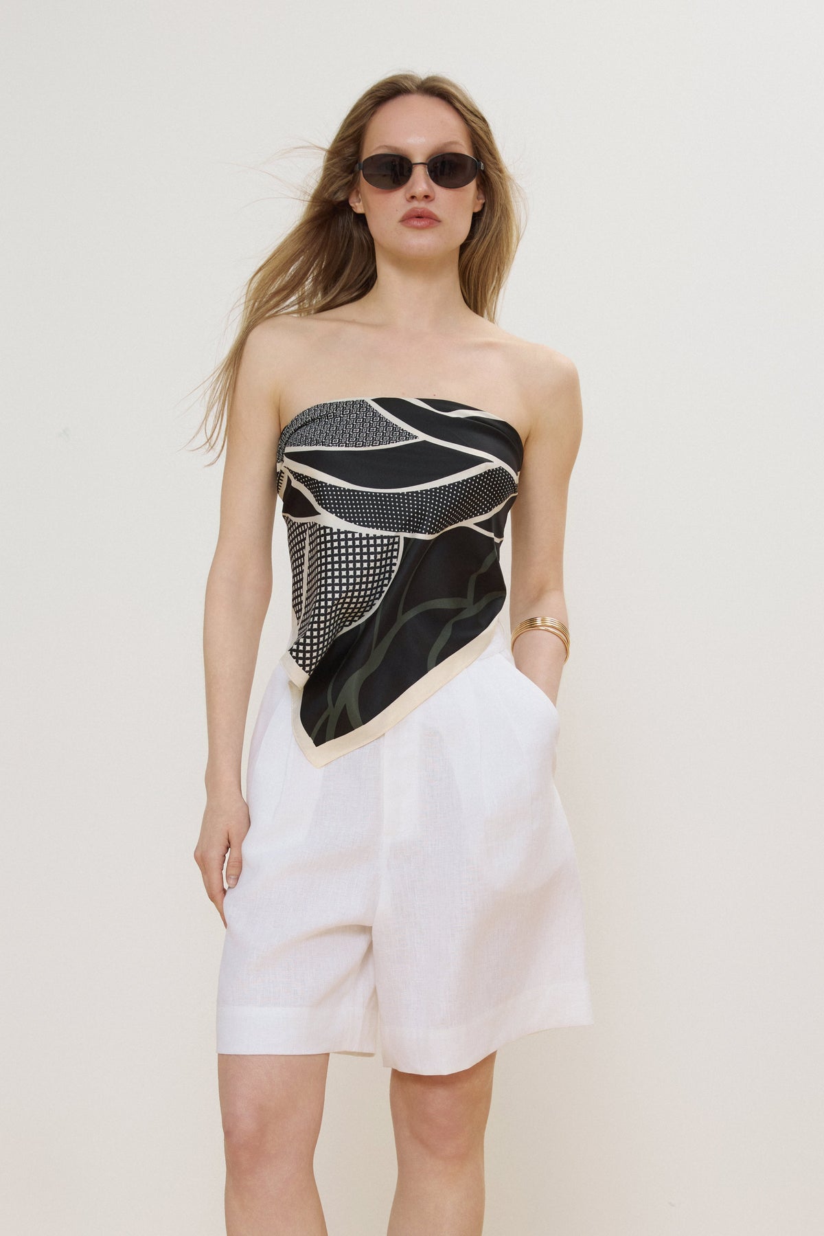 Model trägt das schwarz-beigefarbene Halstuch als stilvolles Bandeau-Oberteil zu weißen Shorts