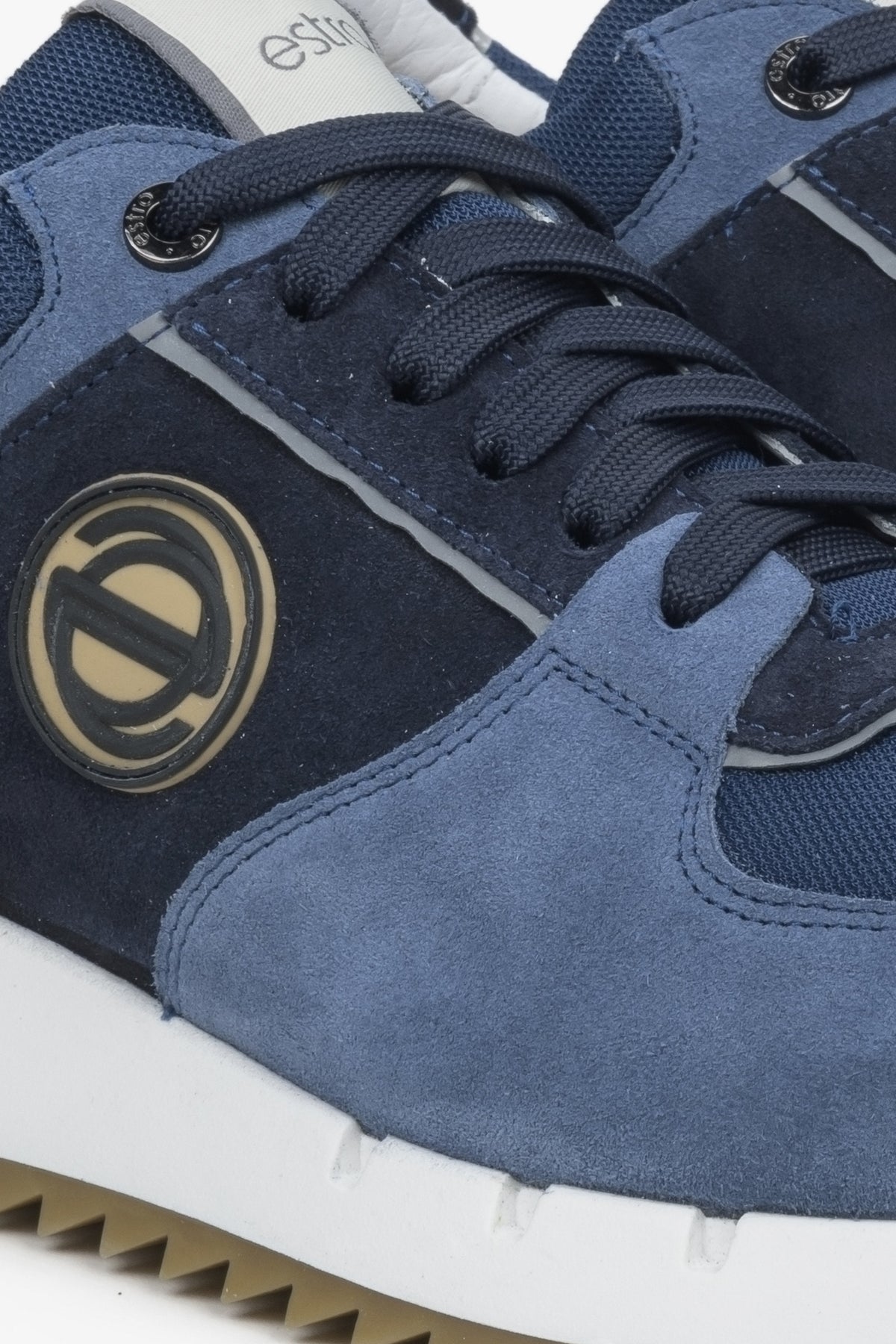 Detailansicht des goldenen Markenlogos am seitlichen Veloursleder der Herren-Sneaker