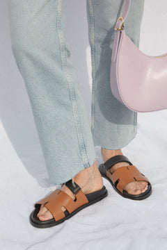 Model trägt die zweifarbigen Lederpantoletten zu hellen Jeans und einer rosa Handtasche