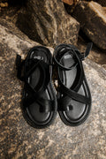 Draufsicht auf das Paar schwarzer Sandalen von Estro am Stein