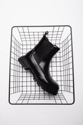 Schwarzer Damen-Chelsea-Boot mit Chunky-Sohle auf einem Drahtwürfel präsentiert