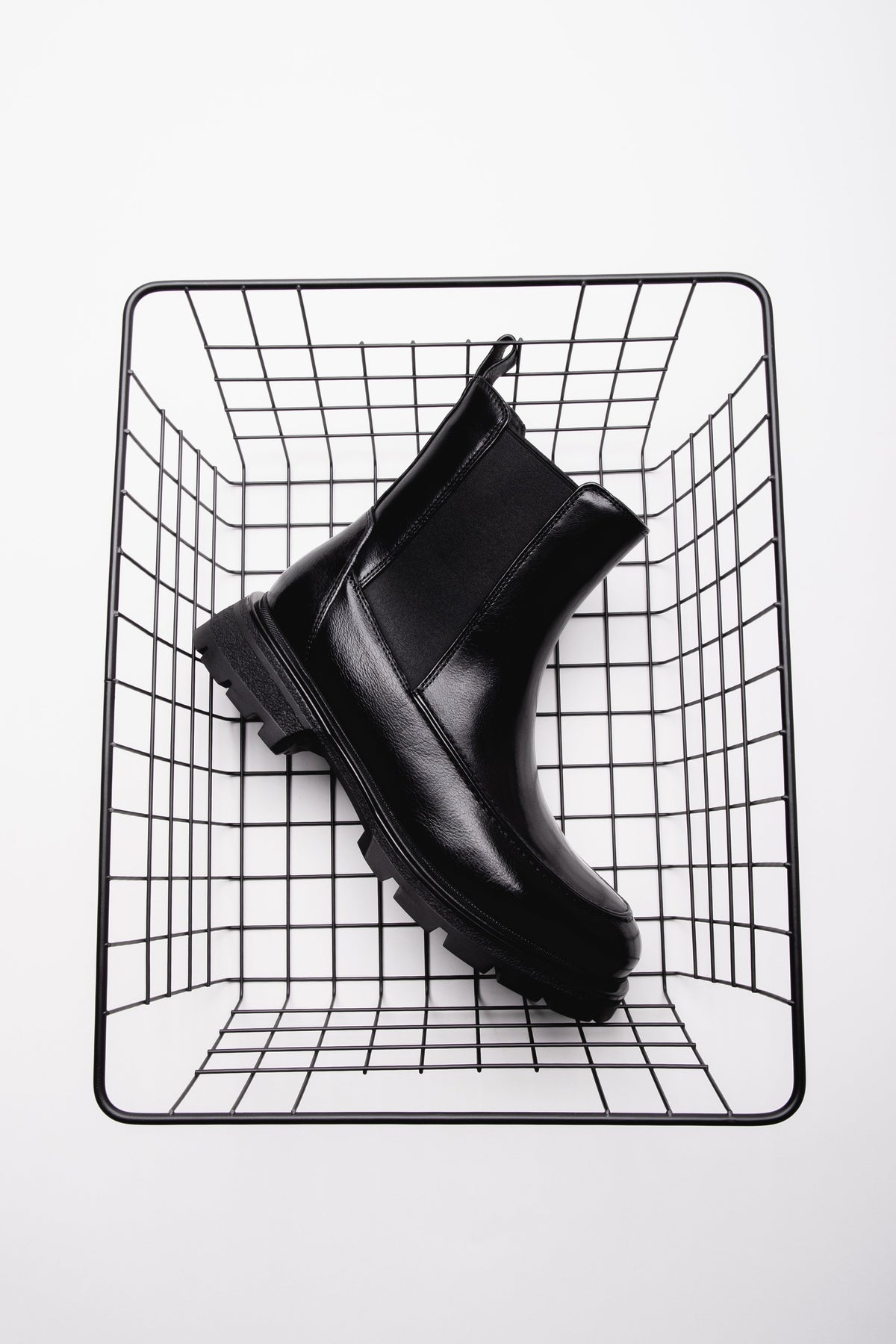 Schwarzer Damen-Chelsea-Boot mit Chunky-Sohle auf einem Drahtwürfel präsentiert