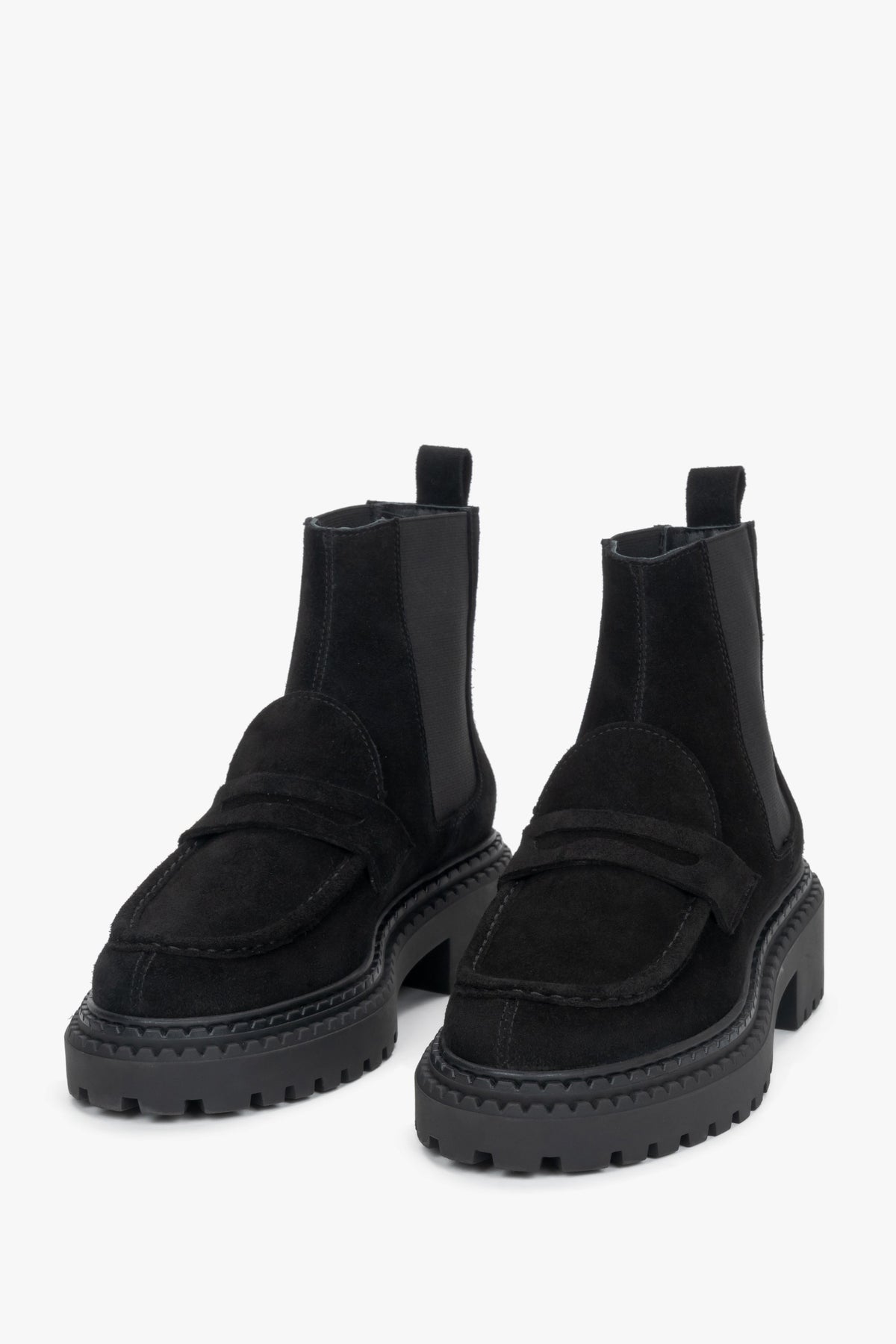 Studioaufnahme von zwei knöchelhohen, schwarzen Damen-Chelsea-Boots aus echtem Veloursleder auf hellem, neutralem Hintergrund.