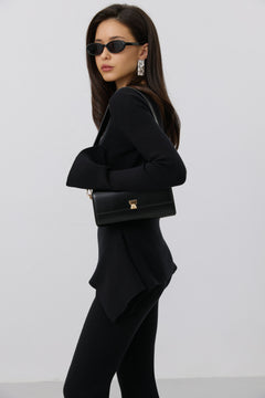 Model im komplett schwarzen Outfit mit Sonnenbrille trägt die schwarze Leder-Clutch elegant unter dem Arm