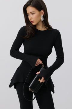 Model hält die elegante schwarze Clutch mit goldenen Details vor sich
