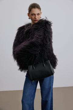 Model trägt die schwarze Handtasche zu einem dunklen, pelzigen Outfit für einen modernen, stilvollen Auftritt
