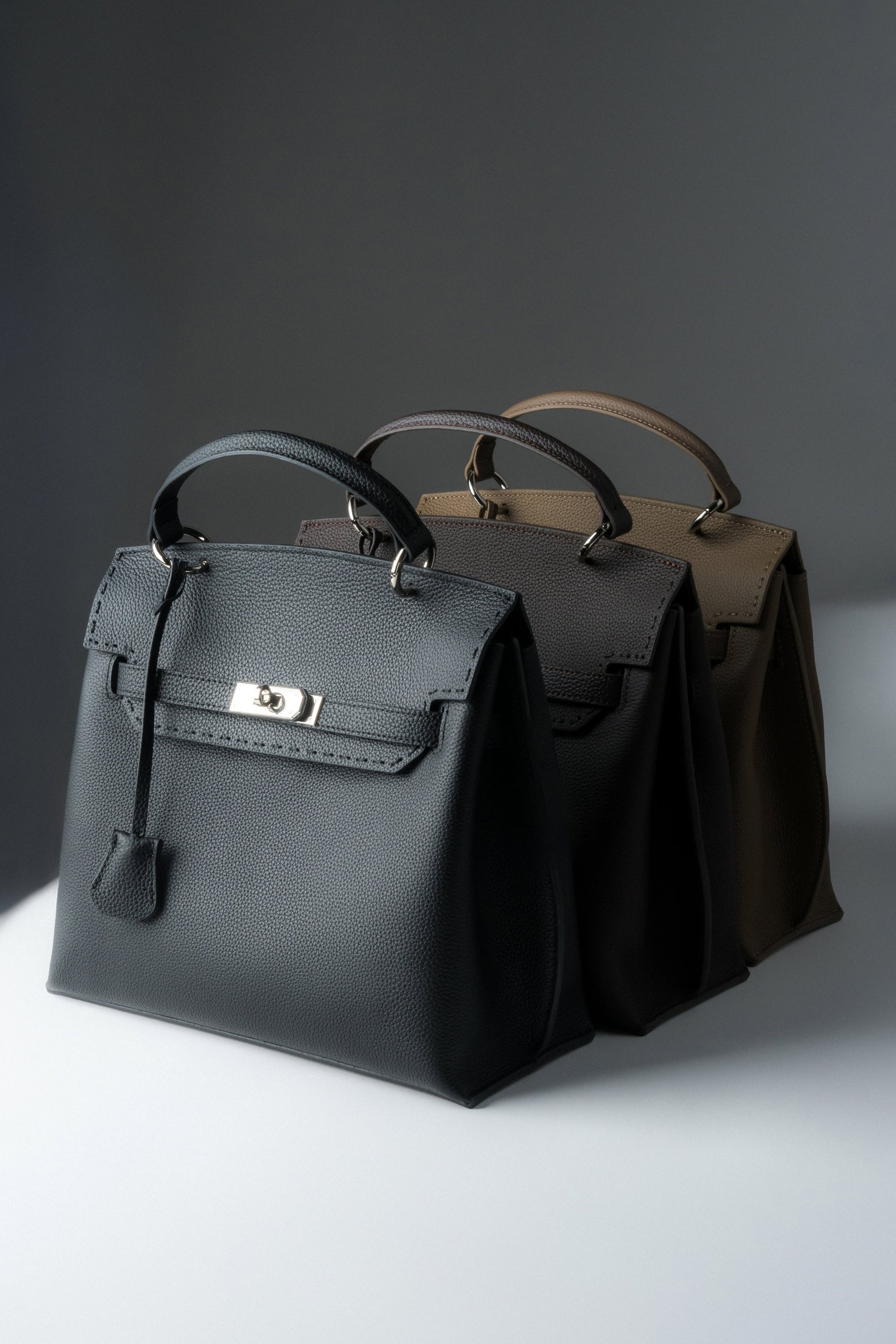 Draufsicht auf drei Varianten der Estro Henkeltasche in Schwarz, Dunkelbraun und Khaki.