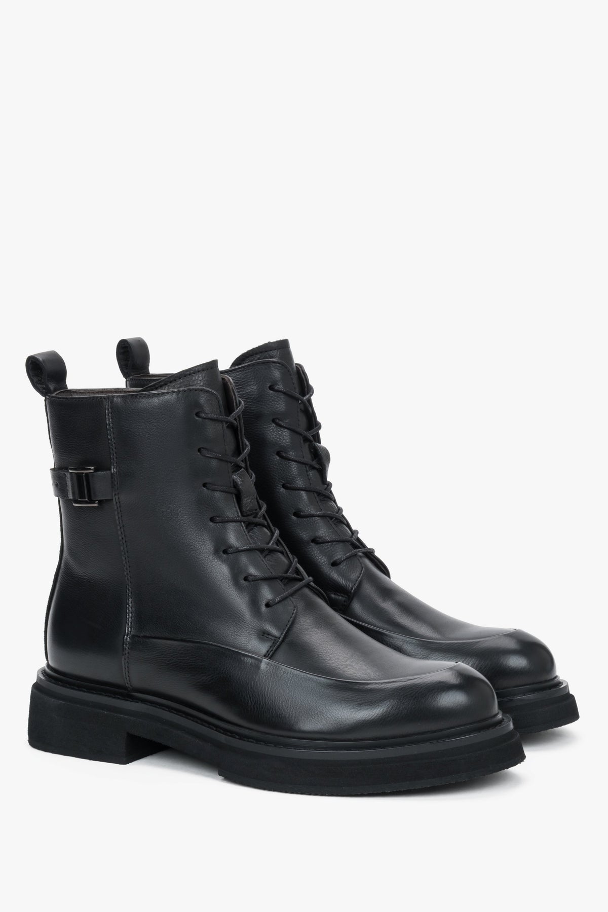 Diagonale Ansicht des Paares schwarzer Leder-Stiefeletten, die die robuste Silhouette und die flache EVA-Sohle zeigt