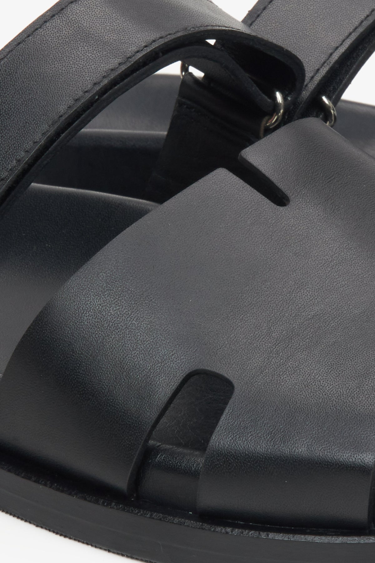 Detailansicht der glatten Lederstruktur und der Ausschnitte der schwarzen Pantoletten