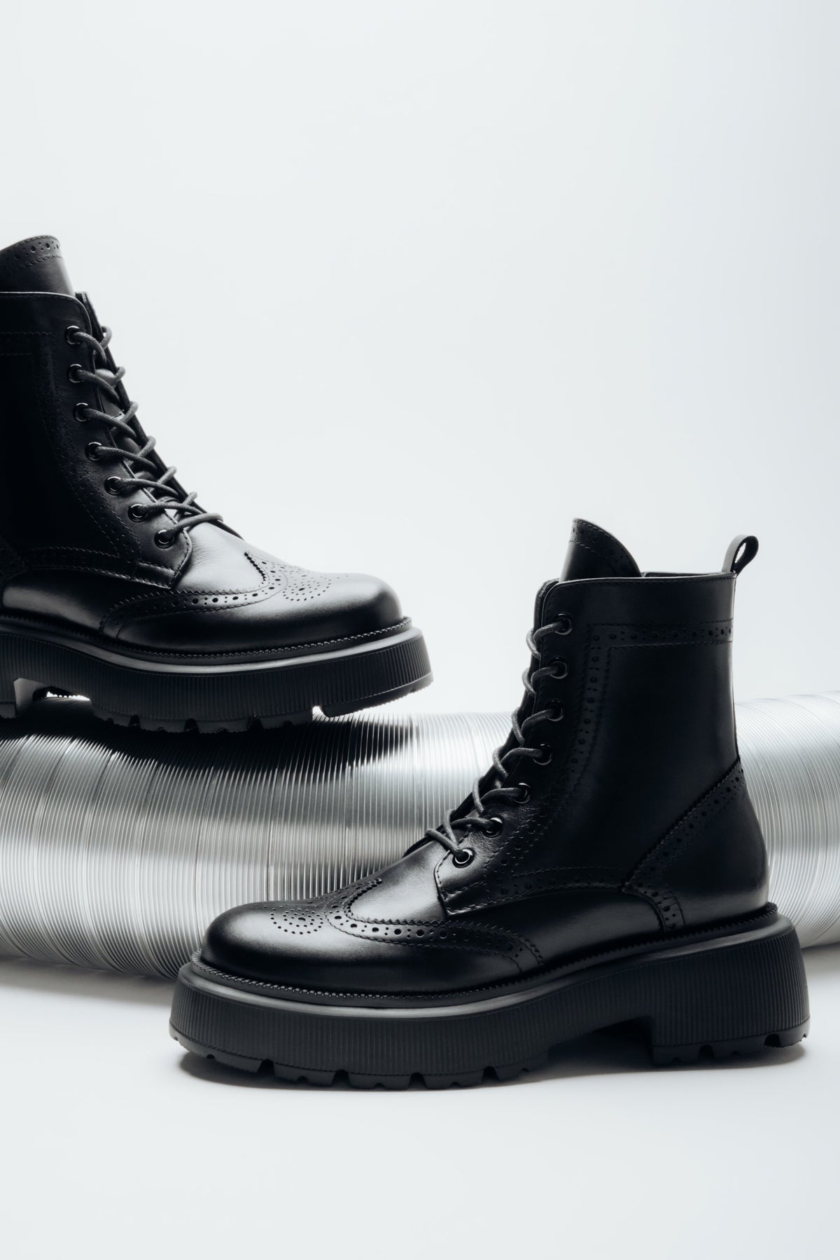 Diagonale Ansicht des Paares schwarzer Schnürstiefeletten aus italienischem Glattleder mit Brogue-Perforationen von Estro