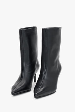 Diagonale Frontalansicht des Paares schwarzer Stiefeletten von schräg oben, die die markante, geometrische Spitze hervorhebt