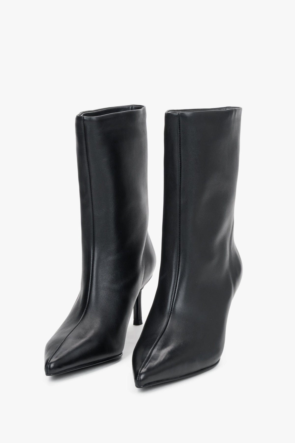Diagonale Frontalansicht des Paares schwarzer Stiefeletten von schräg oben, die die markante, geometrische Spitze hervorhebt