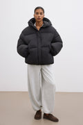 Frontalansicht der schwarzen Damen-Oversize-Jacke mit Kapuze, präsentiert im modernen urbanen Styling 