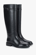 Frontalansicht der edlen schwarzen Damen-Reitstiefel aus Glattleder von Estro mit flachem Absatz und Zierschließe