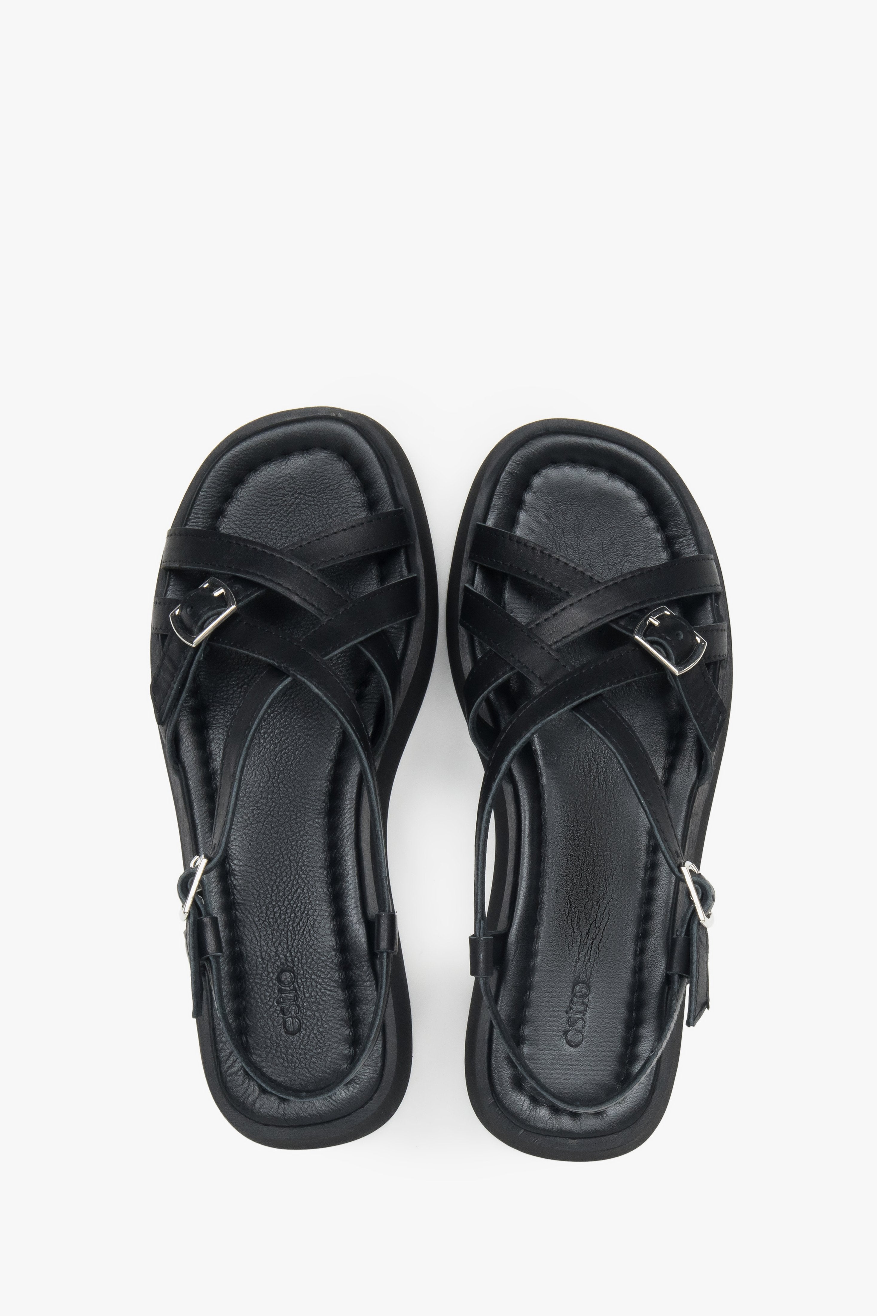 Draufsicht auf das Echtleder-Fußbett und die überkreuzten Riemen der schwarzen Sandalen