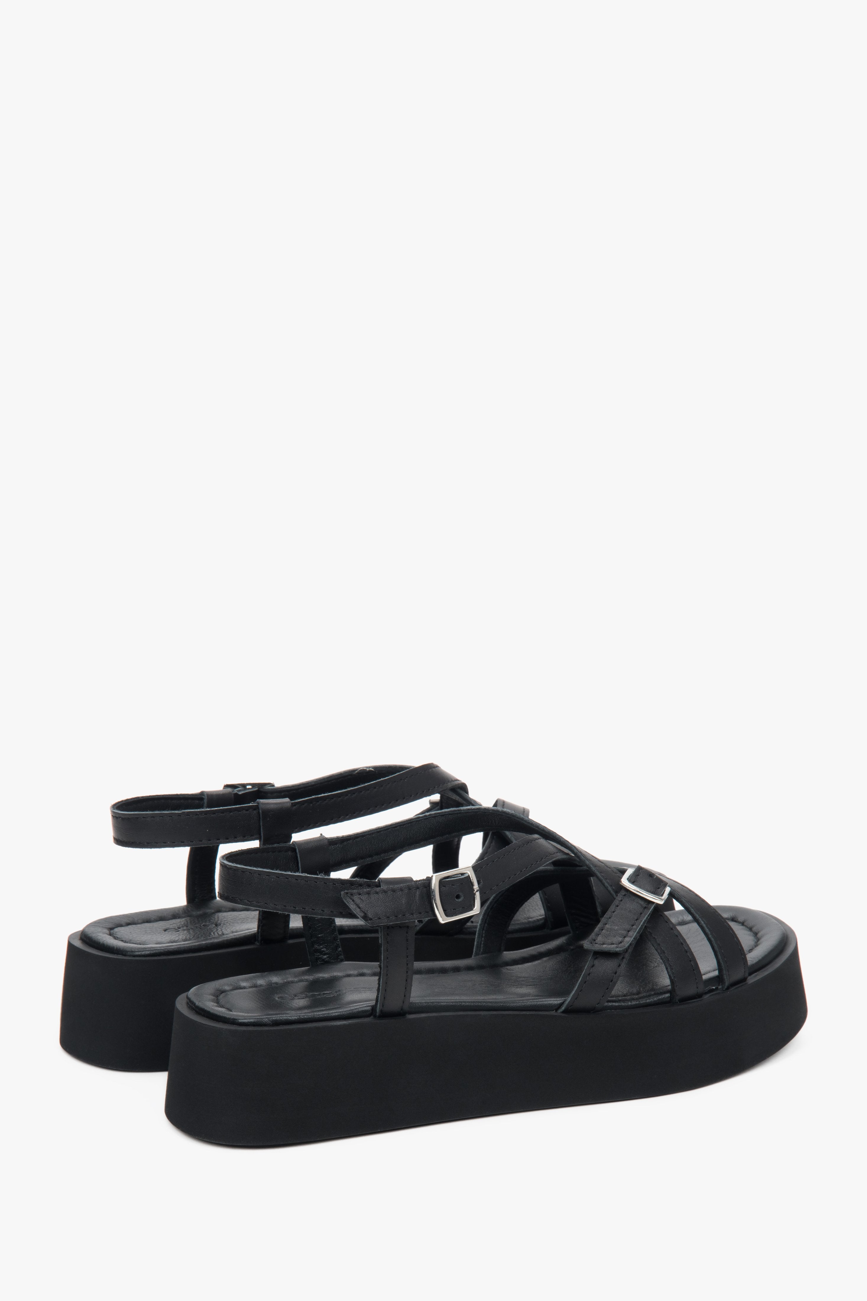 Rückansicht auf das Echtleder-Fußbett und die überkreuzten Riemen der schwarzen Sandalen