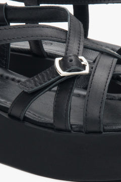 Detailaufnahme der silbernen Schnalle und der Lederriemen an den schwarzen Plateau-Sandalen