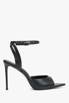 Seitenprofil der schwarzen Stiletto-Sandalen mit Knöchelriemen und goldenen Details.
