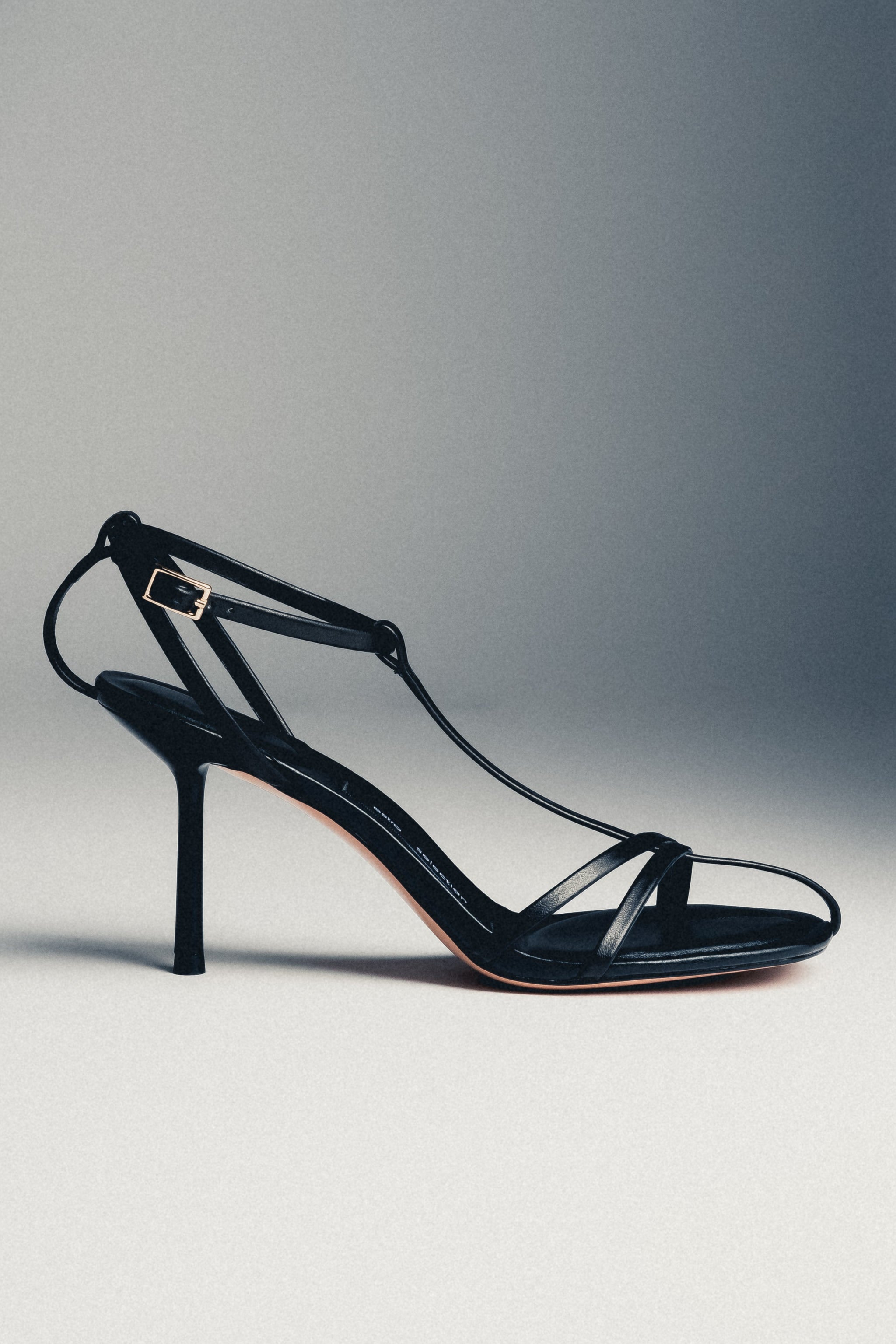 Schwarze Damen-Sandalette aus Echtleder in schräger Ansicht auf grauem Hintergrund