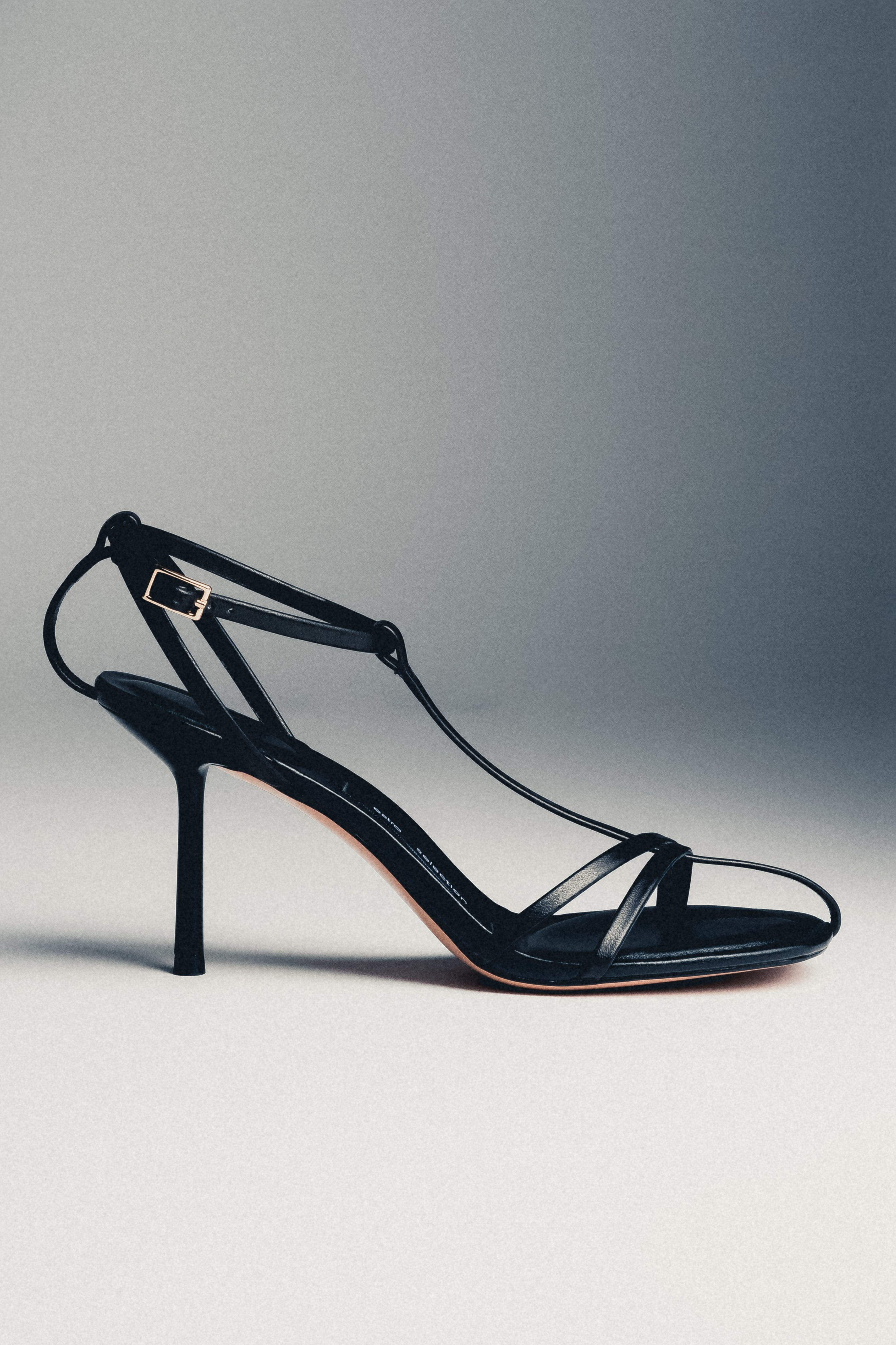 Schwarze Damen-Sandalette aus Echtleder in schräger Ansicht auf grauem Hintergrund