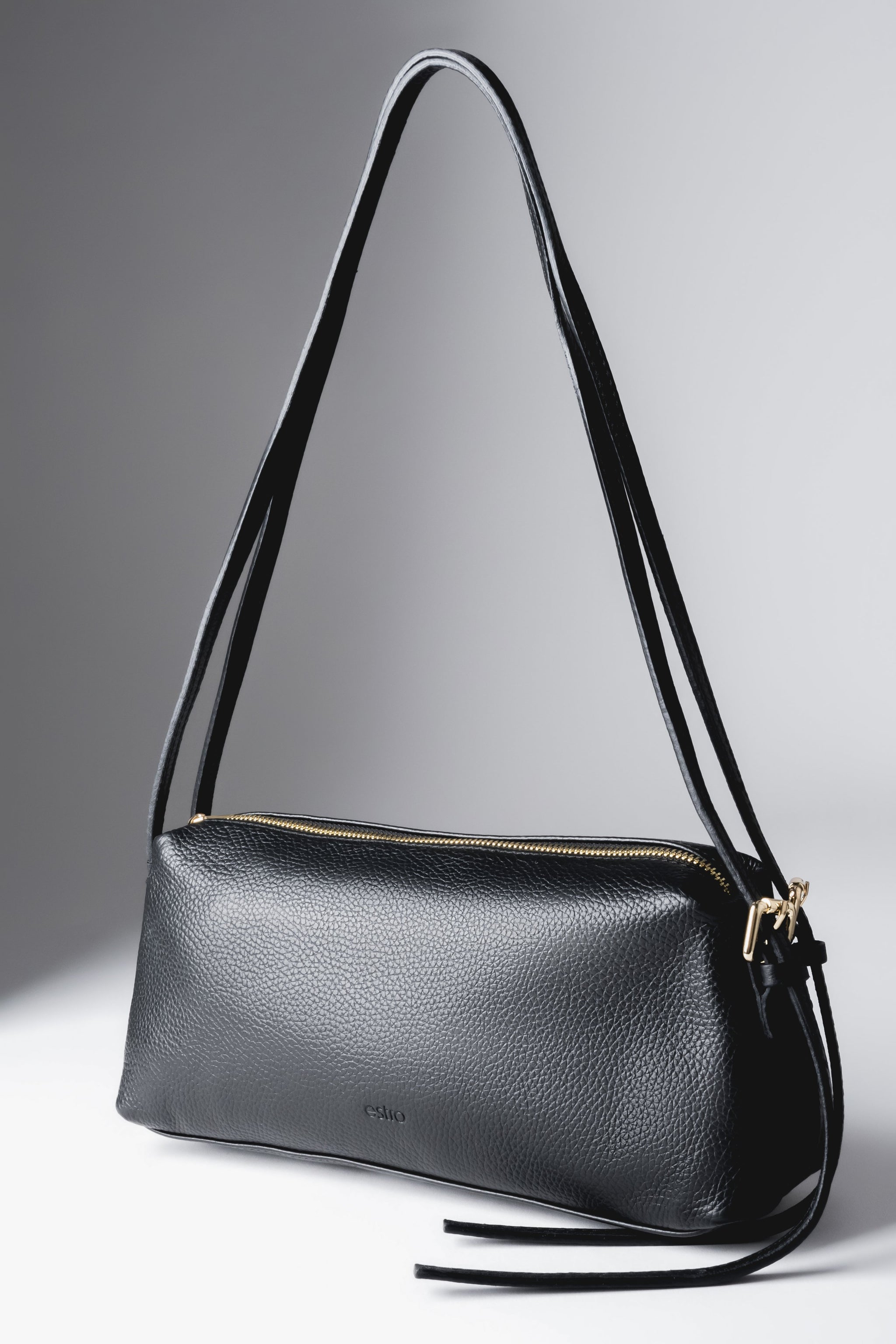 Schrägansicht der schwarzen, länglichen Damen-Schultertasche aus genarbtem italienischem Echtleder mit langem Riemen und goldenen Details
