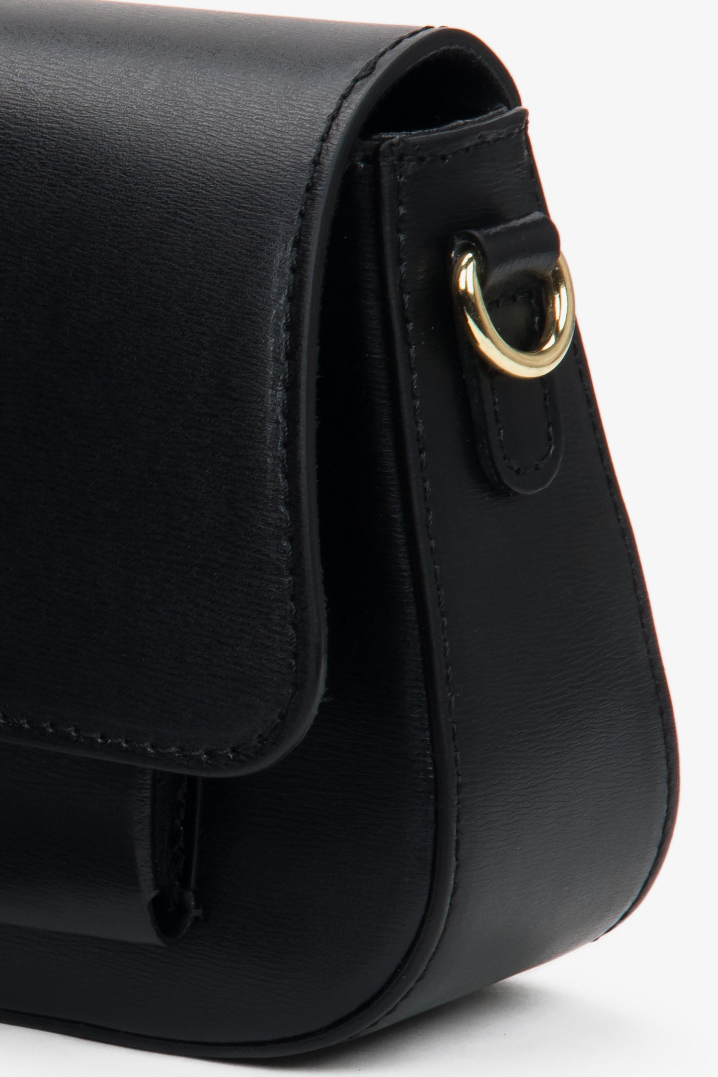 Nahaufnahme der seitlichen Partie der schwarzen Leder-Schultertasche mit Fokus auf die präzise Nahtführung, die glatte Struktur und den goldenen Befestigungsring