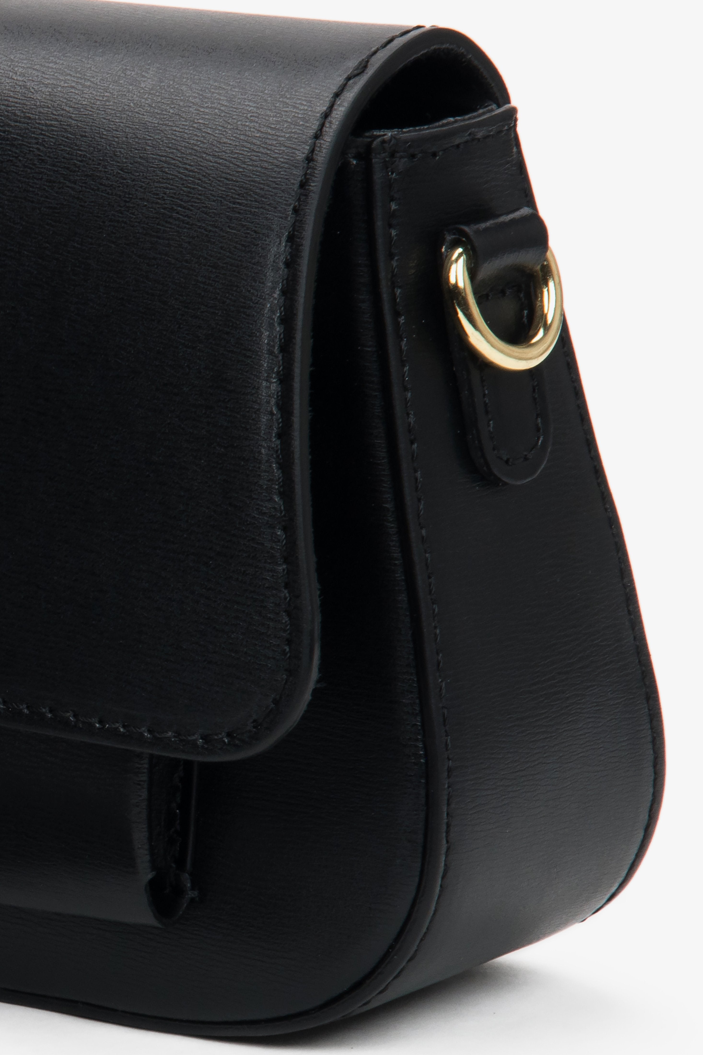 Nahaufnahme der seitlichen Partie der schwarzen Leder-Schultertasche mit Fokus auf die präzise Nahtführung, die glatte Struktur und den goldenen Befestigungsring