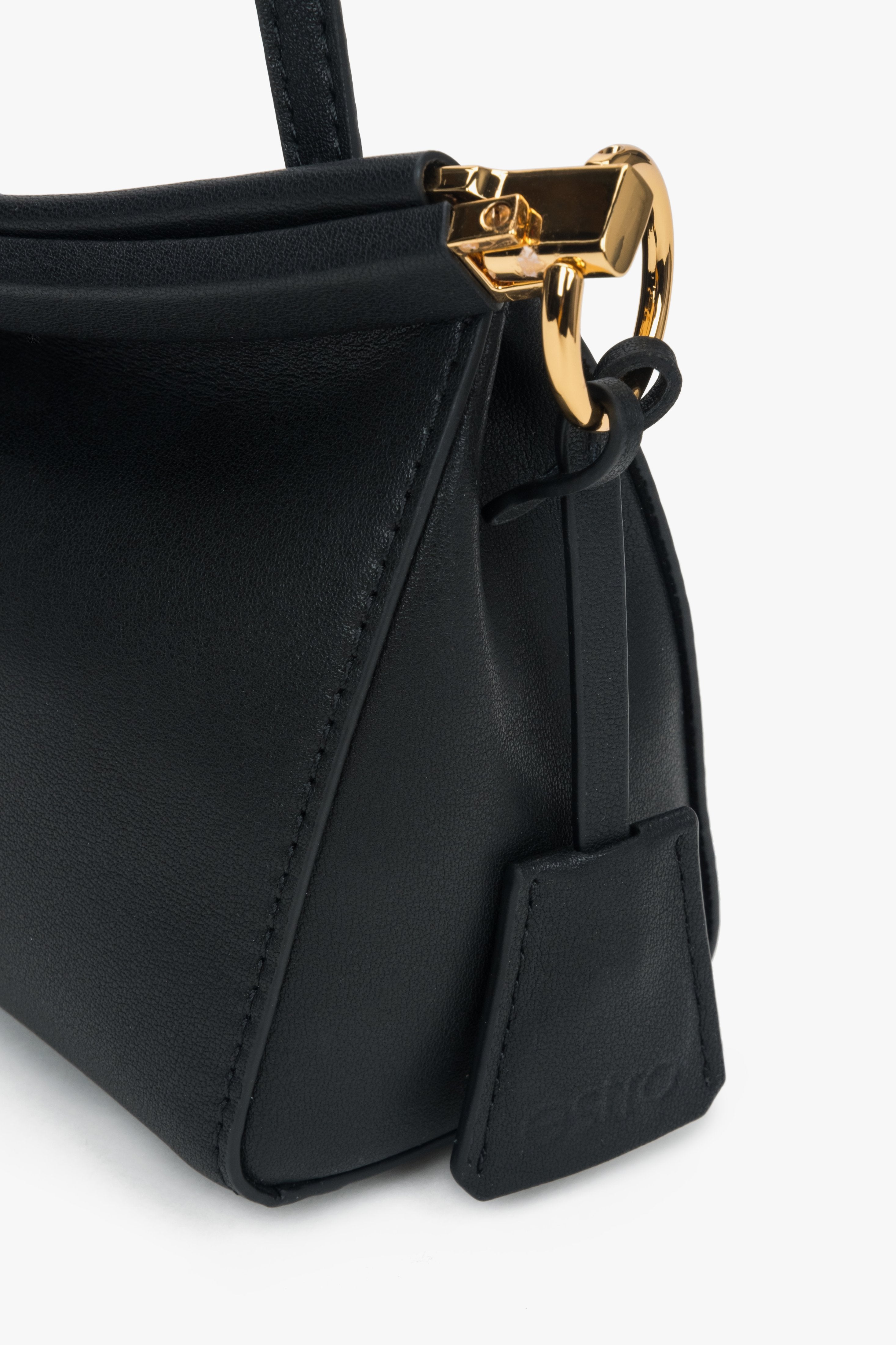 Detailaufnahme der goldenen Riemenbefestigung an der schwarzen Estro Handtasche.