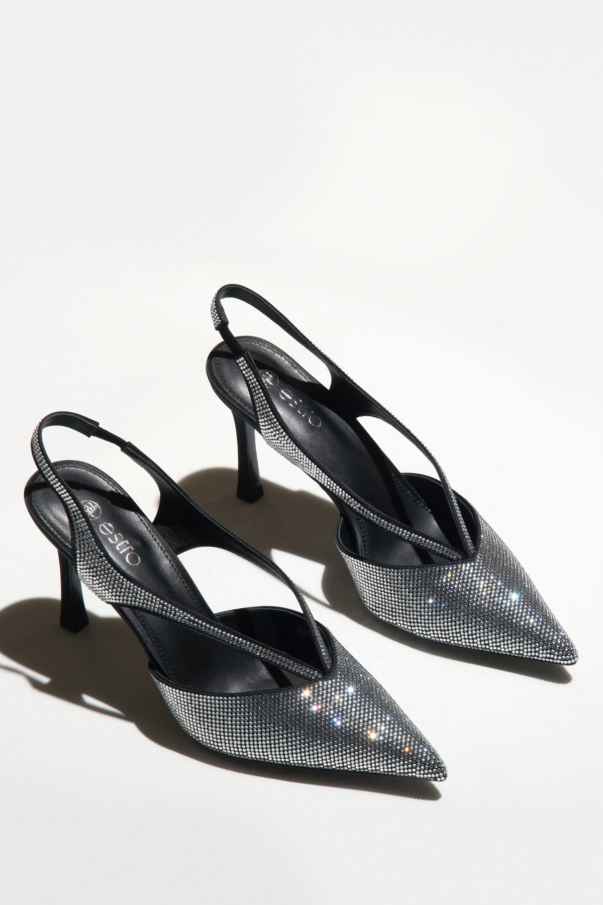 Zwei schwarze Slingback-Pumps mit funkelnden Kristallen auf hellem Hintergrund