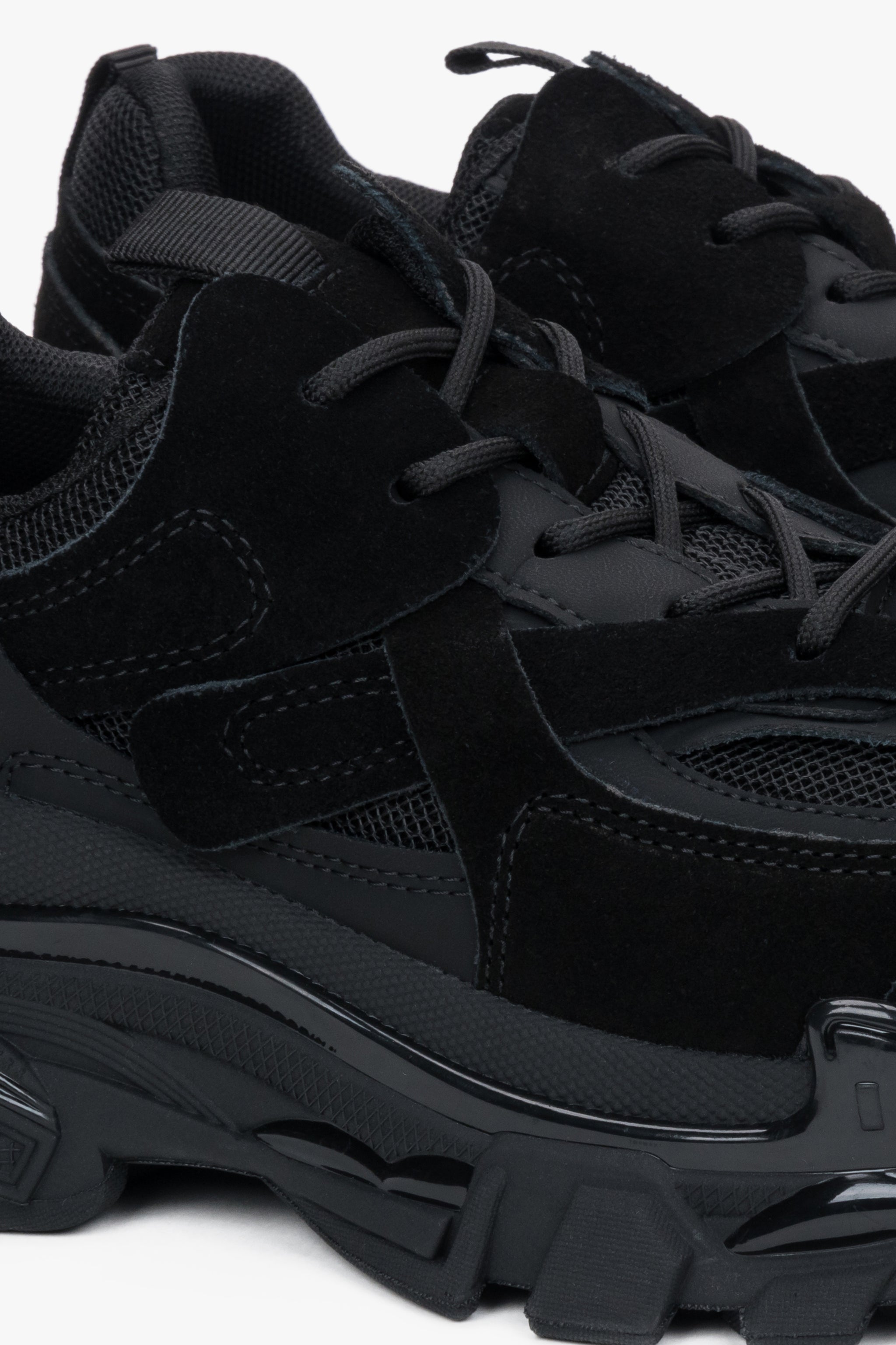 Nahaufnahme des schwarzen Sneakers mit Fokus auf den Materialmix aus Velours und Mesh sowie die markante Profilsohle 