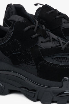 Nahaufnahme des schwarzen Sneakers mit Fokus auf den Materialmix aus Velours und Mesh sowie die markante Profilsohle 