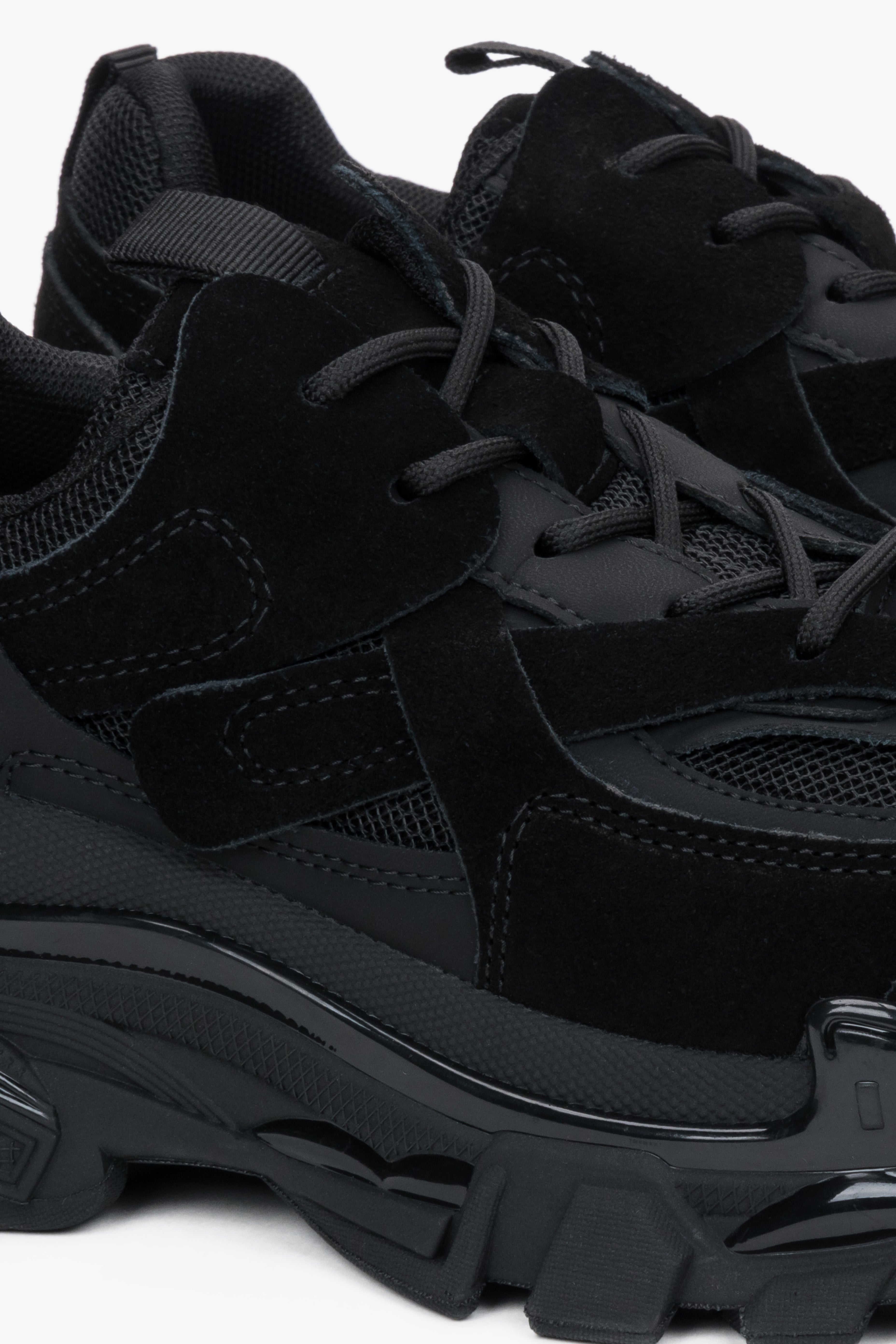 Nahaufnahme des schwarzen Sneakers mit Fokus auf den Materialmix aus Velours und Mesh sowie die markante Profilsohle 