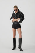 Model in Oversized-Lederjacke und Shorts präsentiert die schwarzen Stiefel mit Absatz