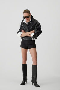 Model in Oversized-Lederjacke und Shorts präsentiert die schwarzen Stiefel mit Absatz
