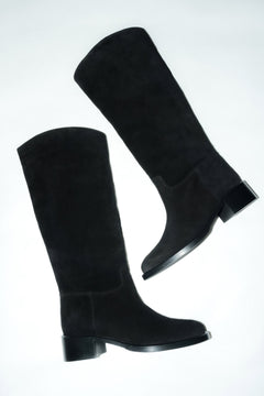 Künstlerische Draufsicht des schwarzen Veloursstiefel-Paares auf hellem Untergrund 