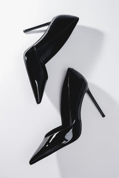 Künstlerische Draufsicht auf das Paar schwarzer Damen-Stilettos aus Lackleder