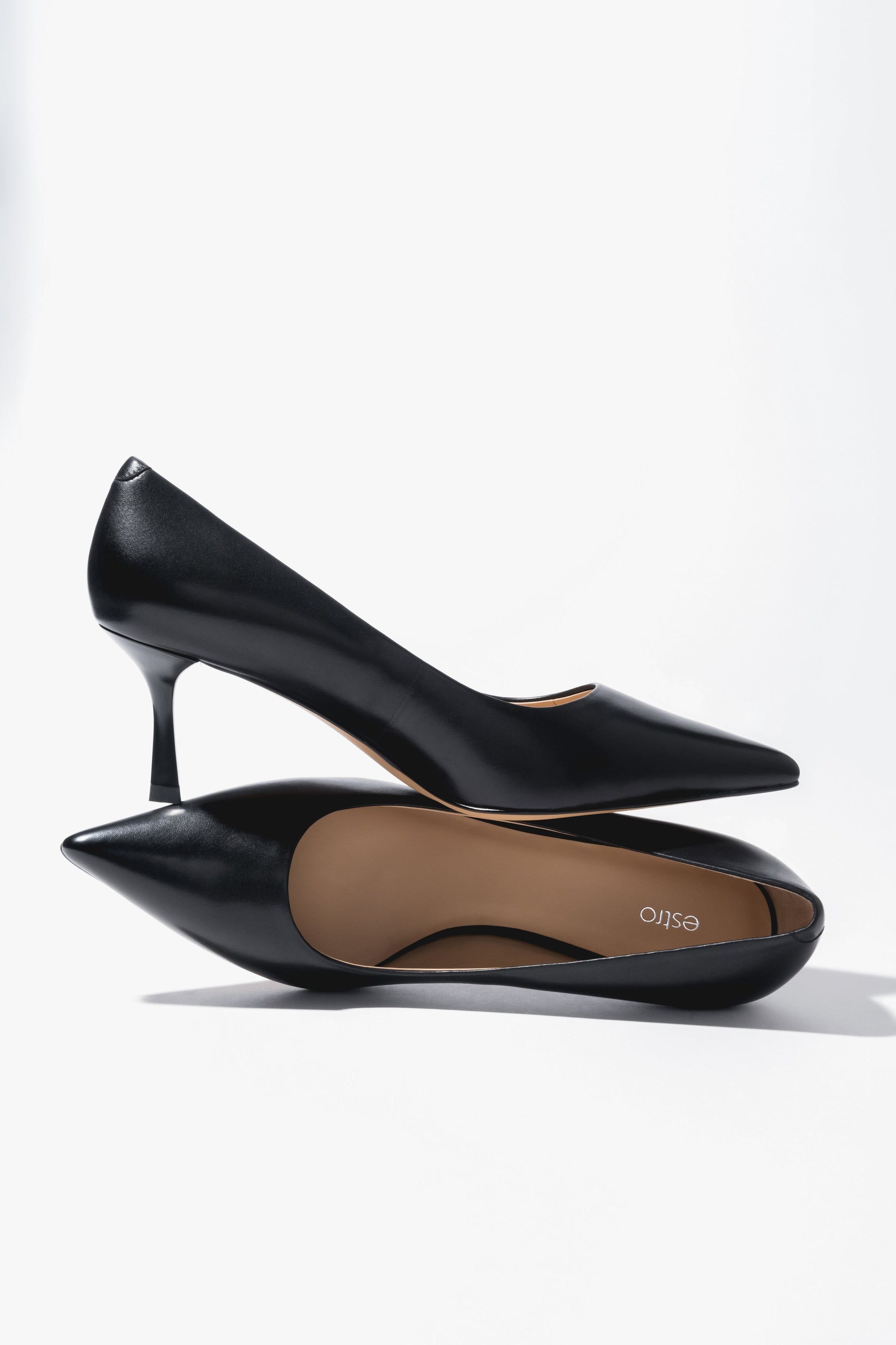 Kreative Ansicht der schwarzen Damen-Stilettos aus Echtleder, übereinander platziert mit Fokus auf die spitze Kappe und den 7 cm hohen Absatz 